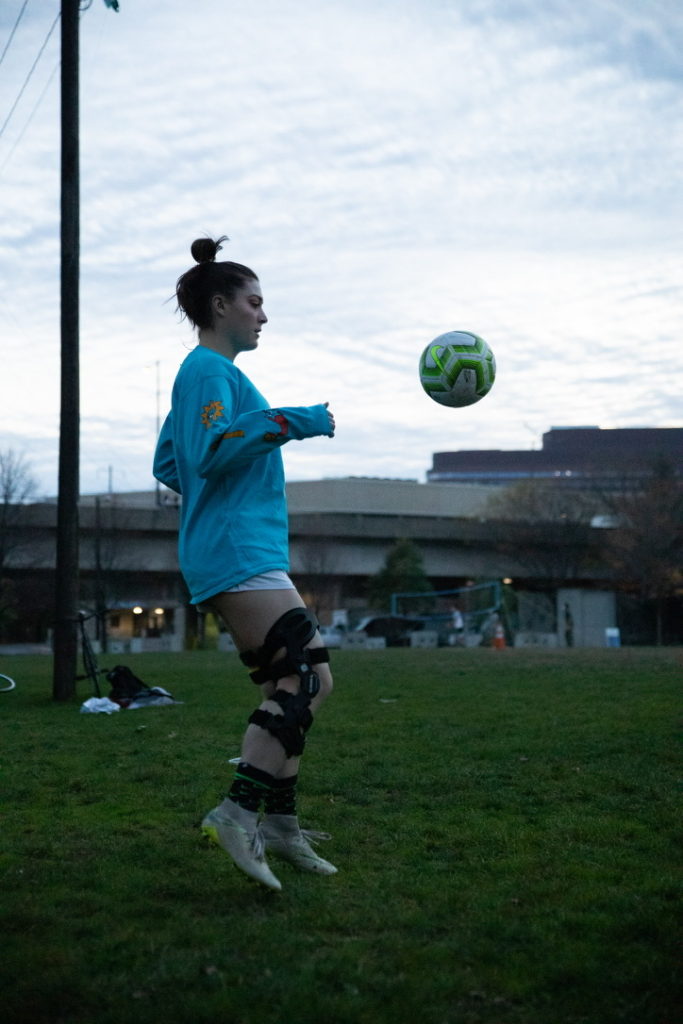 female athlete playing soccer with knee brace